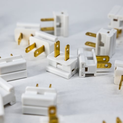 White electrical plugs and connectors with gold prongs, suitable for lighting fixtures and electrical systems.